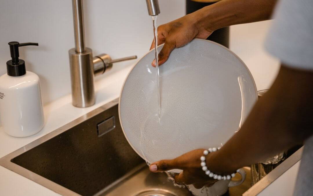 Woman washing a white plate in the sink